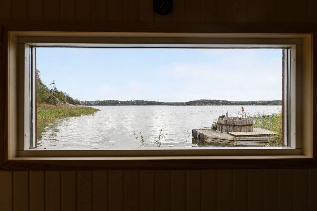 Utsikt över viken och badtunnan på bryggan genom bastuns fönster