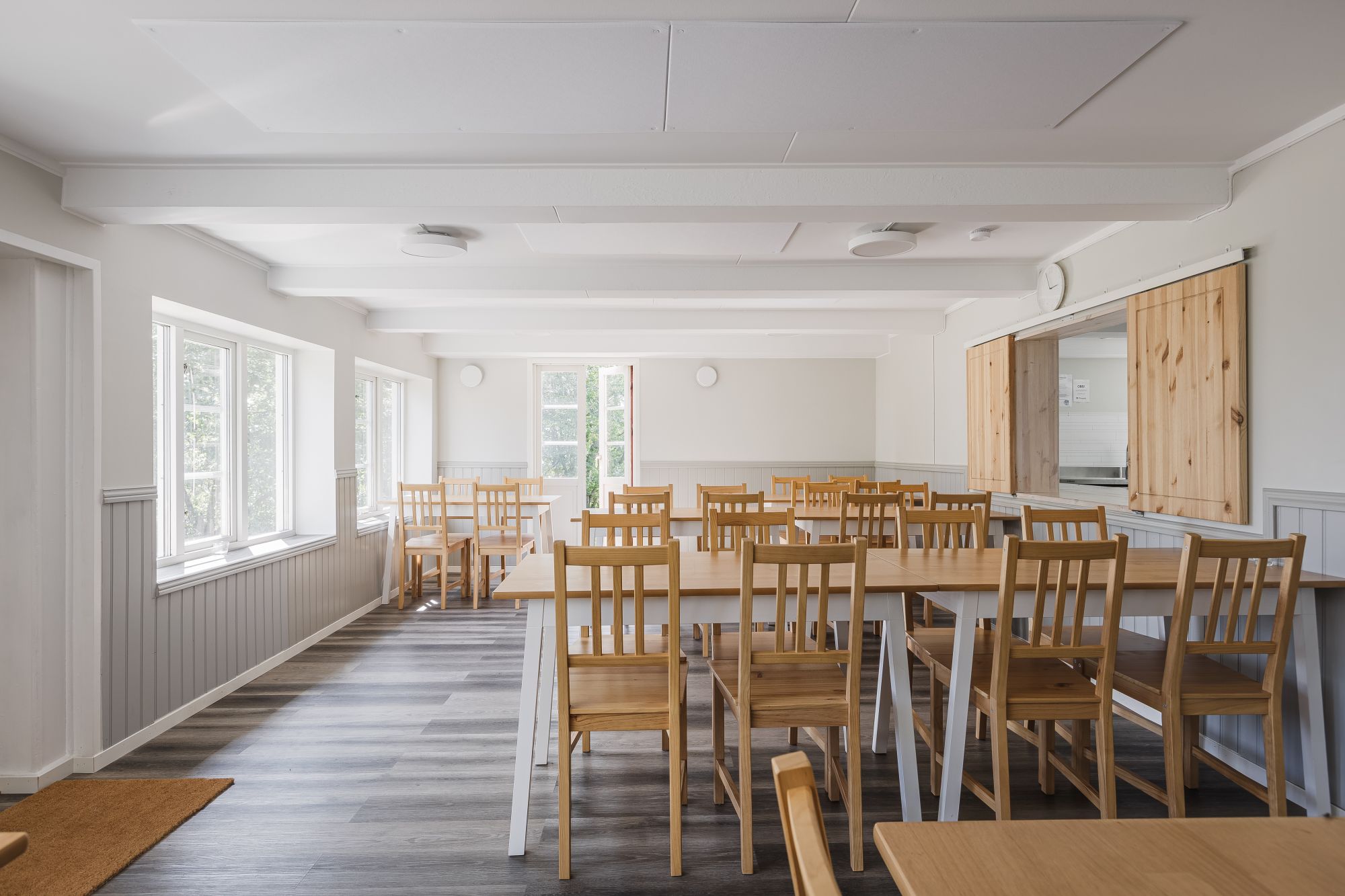 Strandköket – matsalen med bordsrader och serveringslucka
